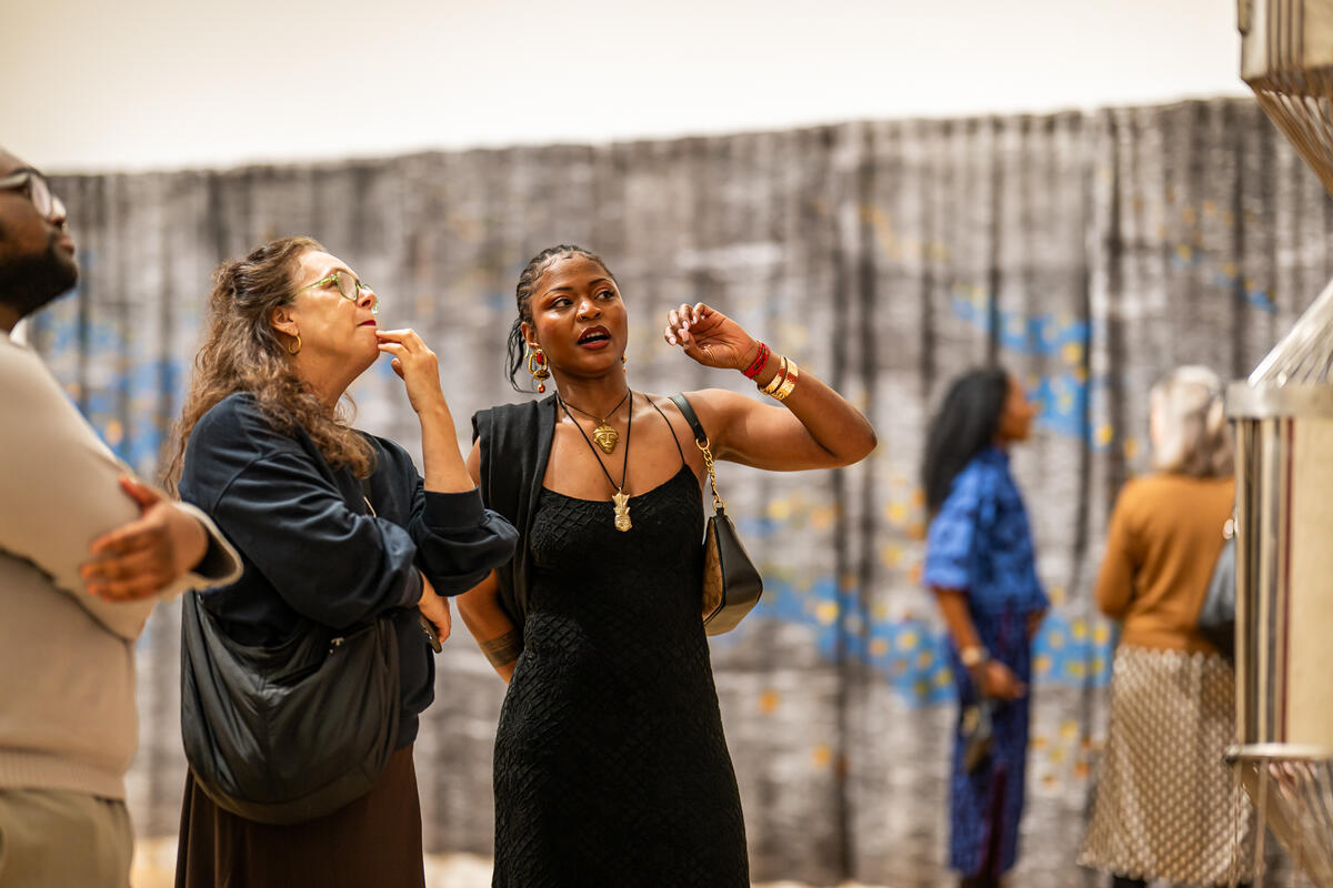 An artist tells a visitor about her iron statue.