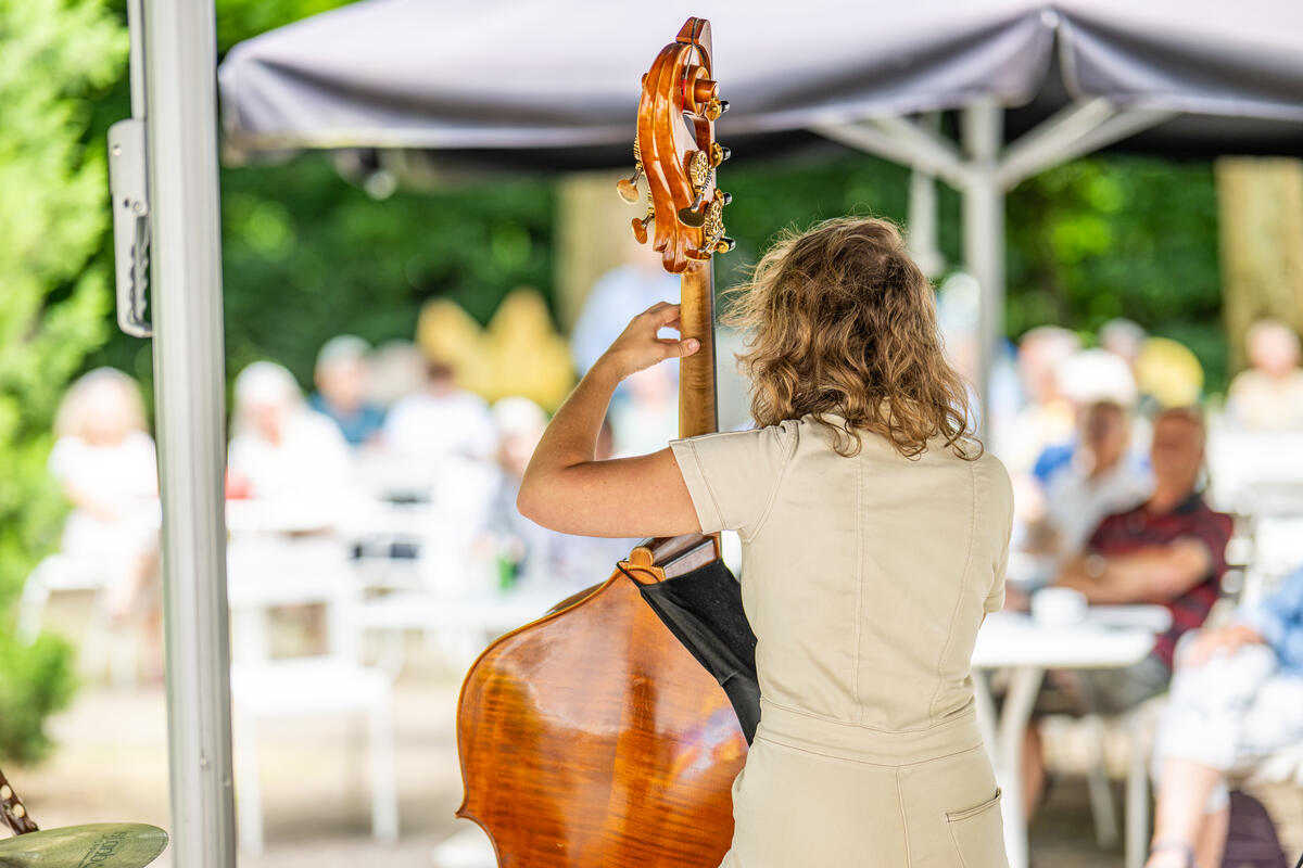 Een vrouw speelt de contrabas op het terras van Kasteel het Nijenhuis.
