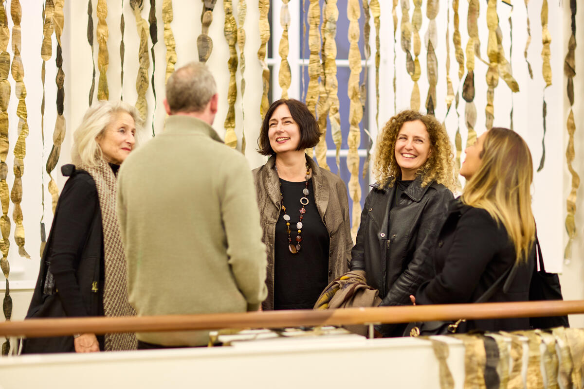 Een groep mensen staan op de balustrade en praten met de bestuurder van De Fundatie. Ze zijn omringd met gouden slingers.
