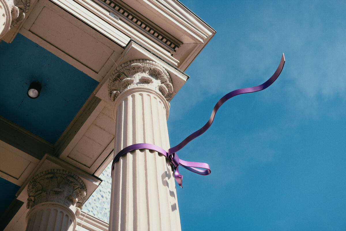 Ein Foto von unten vom Geb&auml;ude und den S&auml;ulen des Museum de Fundatie. Ein violettes Metallband h&auml;ngt um einen der Pfeiler und scheint im Wind zu flattern.