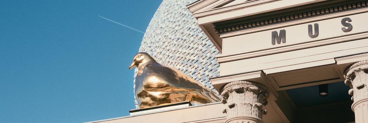 Ein Detail der Skulptur der goldenen Friedenstaube, die auf dem Dach des Museums der FUndation sitzt. Der hellblaue Aufbau und die S&auml;ulen sind auf der rechten Seite des Bildes zu sehen.