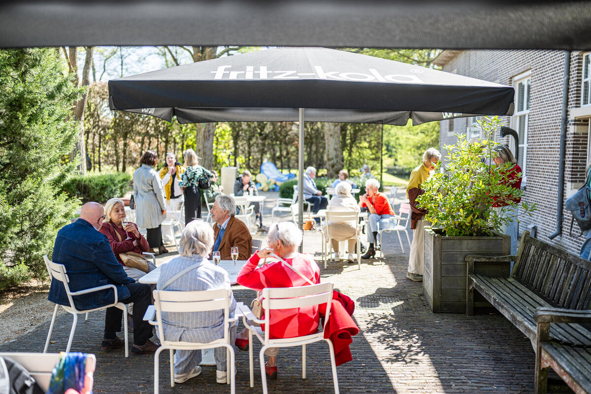 Auf der Terrasse des Schlosses Nijenhuis sitzt man inmitten von Gr&uuml;npflanzen.