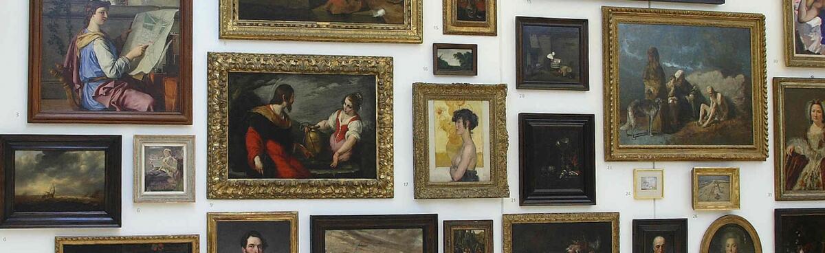 Eine wei&szlig;e Wand mit Dutzenden von Gem&auml;lden in verschiedenen Gr&ouml;&szlig;en aus der eigenen Sammlung. Bei den meisten Gem&auml;lden handelt es sich um Portr&auml;ts aus dem 17., 18. und 19. Jahrhundert.