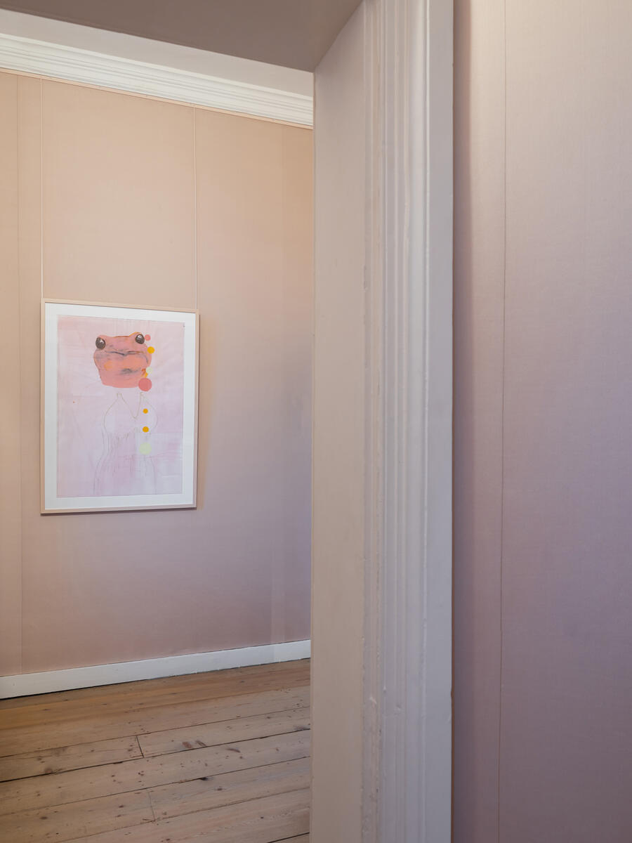 In einem Raum mit hellrosa W&auml;nden h&auml;ngt ein Aquarell von Q.S. Seraphine, das einen rosa Frosch zeigt.