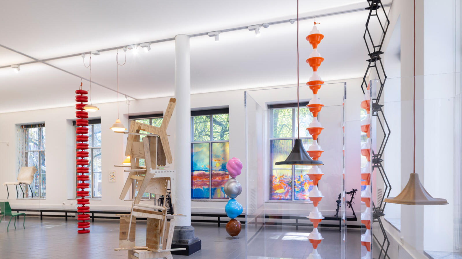 Verschillende kleurrijke beelden en kunstwerken hangen in de ruimte van de grond naar plafond.