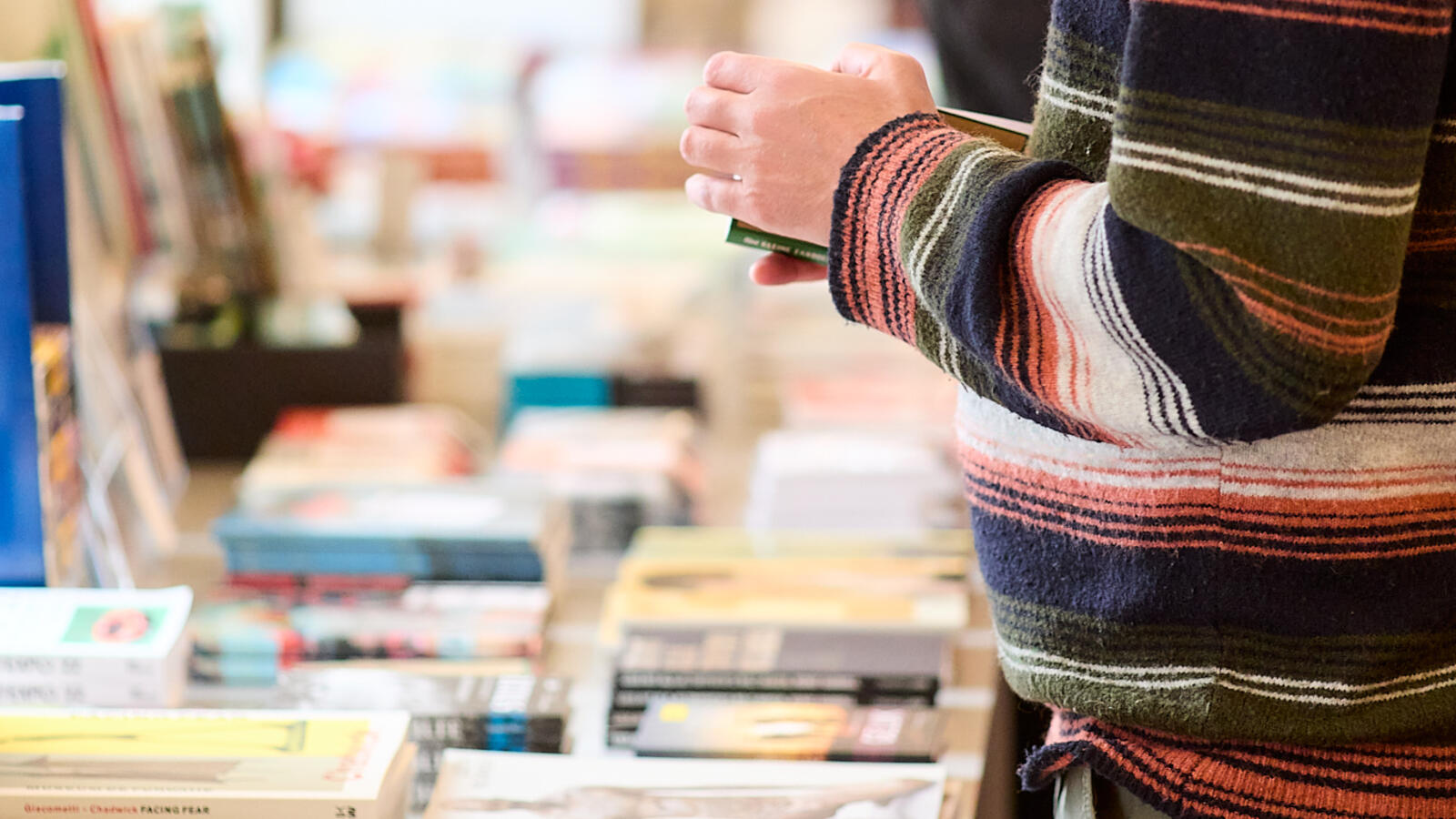 Ein Besucher steht neben einem B&uuml;chertisch im Museumsshop und schaut sich ein Buch an.