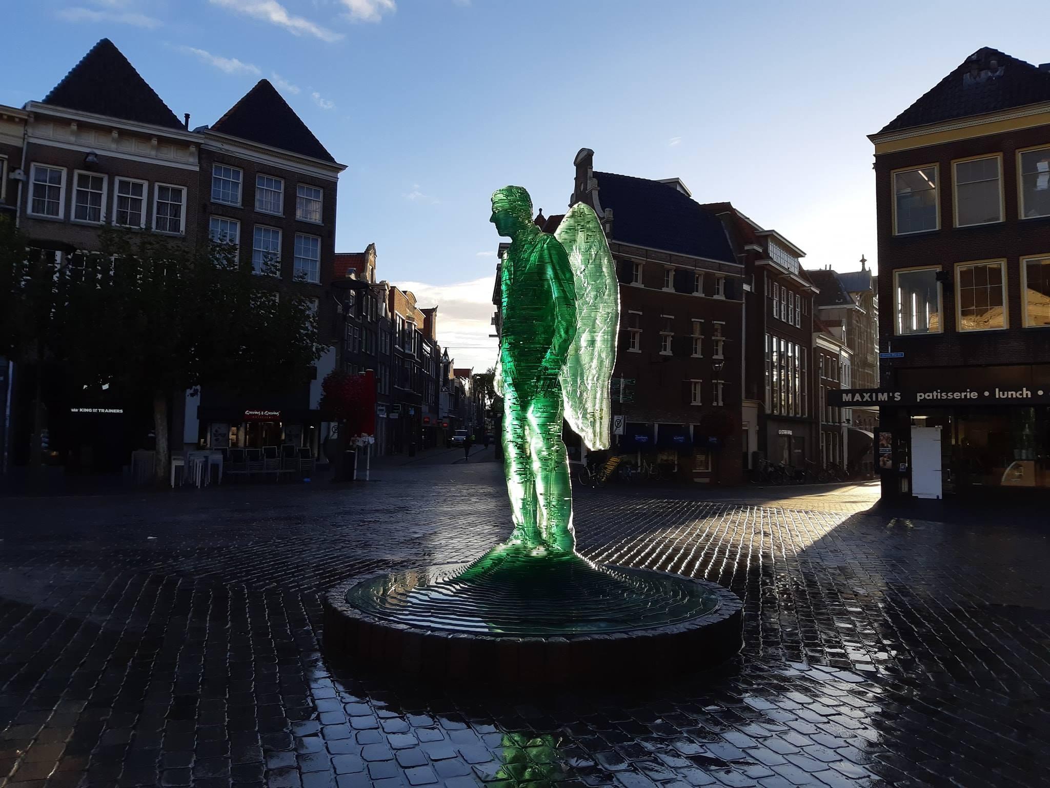 Der Glasengel von Herman Lamers steht in der Mitte des Marktplatzes von Zwolle. Die gr&uuml;ne Statue eines Mannes mit Fl&uuml;geln wird in der Abendd&auml;mmerung wundersch&ouml;n beleuchtet.
